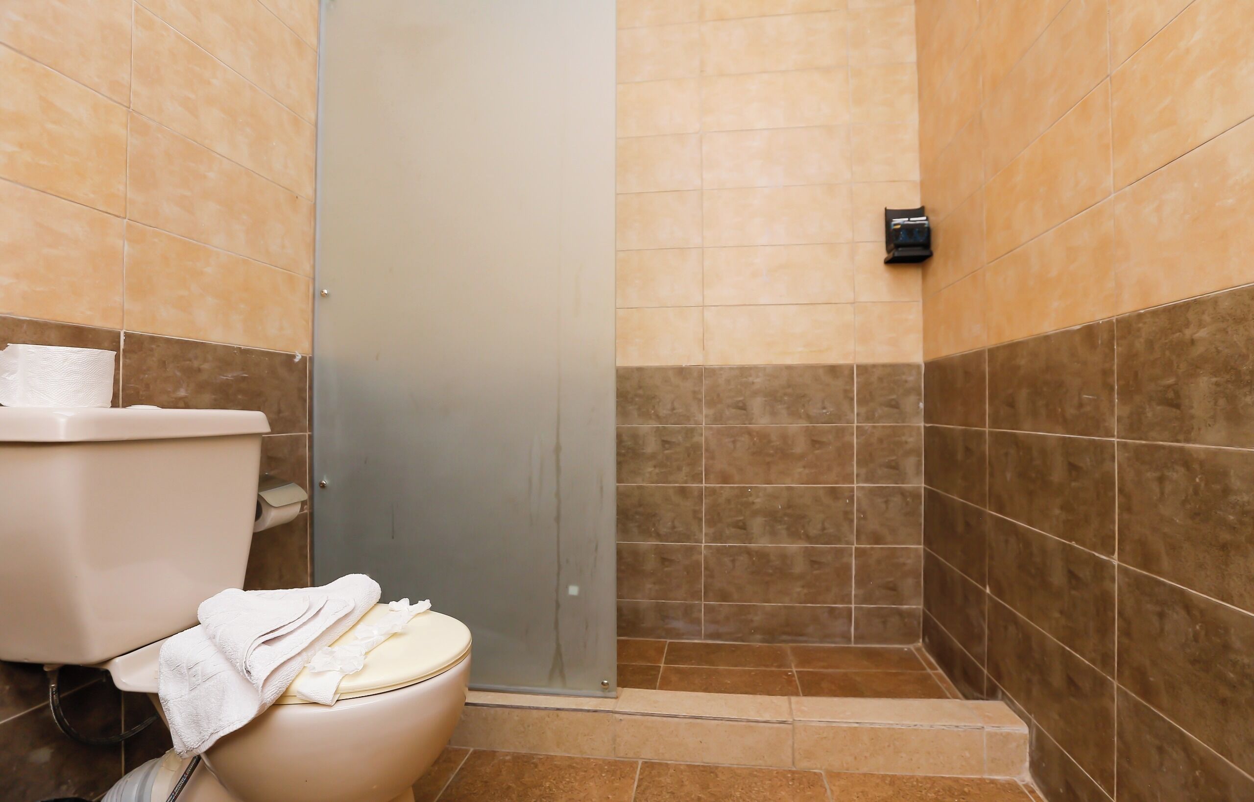Un baño con inodoro, toalla y zona de ducha.
