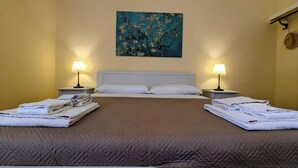 A double bed with a brown quilt, two bedside tables with lamps, a headboard, and a painting of flowers on the wall. - Cottage Sant Elia - Country Retreat  (Sicilia)
