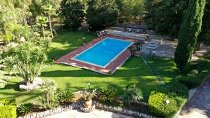 A rectangular swimming pool with a brick border, surrounded by a well-maintained lawn and various plants. - Cottage Sant Elia - Country Retreat  (Sicilia)