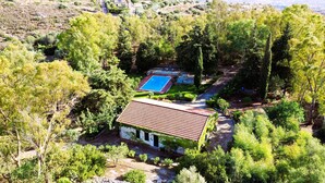 A villa surrounded by dense greenery, featuring a swimming pool and a patio area. - Cottage Sant Elia - Country Retreat  (Sicilia)