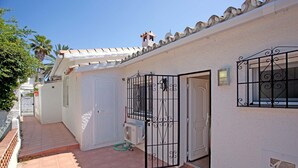 A narrow, tiled courtyard with a white building featuring a metal gate and a small air conditioning unit. - Holiday Home Marbella Near Sand Beach (Marbella)