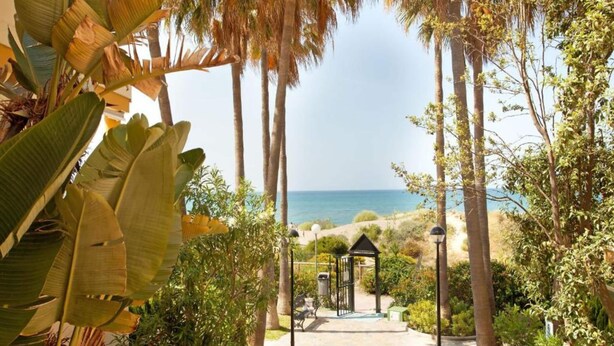 A pathway leading to a beach with palm trees and a gazebo. - Holiday Home Marbella Near Sand Beach (Marbella)
