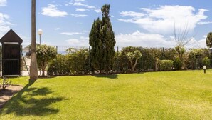 A well-maintained grassy area with a tall tree, a small shed, and a fence. - Holiday Home Marbella Near Sand Beach (Marbella)