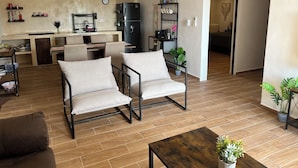 A modern living room with a sofa, a coffee table, and a dining area with a kitchen in the background. - Modern&Quiet full Apartment with Pool in Punta Sur, relax and enjoy this place (Isla Mujeres)