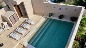 A swimming pool with lounge chairs and a small garden area. - Modern&Quiet full Apartment with Pool in Punta Sur, relax and enjoy this place (Isla Mujeres)