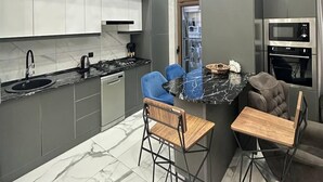A modern kitchen with a central island, bar stools, and a built-in oven. - Tashkent city Bulevard 144 RNB estate (Tashkent)