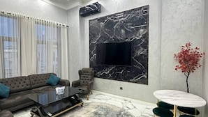 A modern living room with a sofa, coffee table, TV, and a round rug. - Tashkent city Bulevard 144 RNB estate (Tashkent)