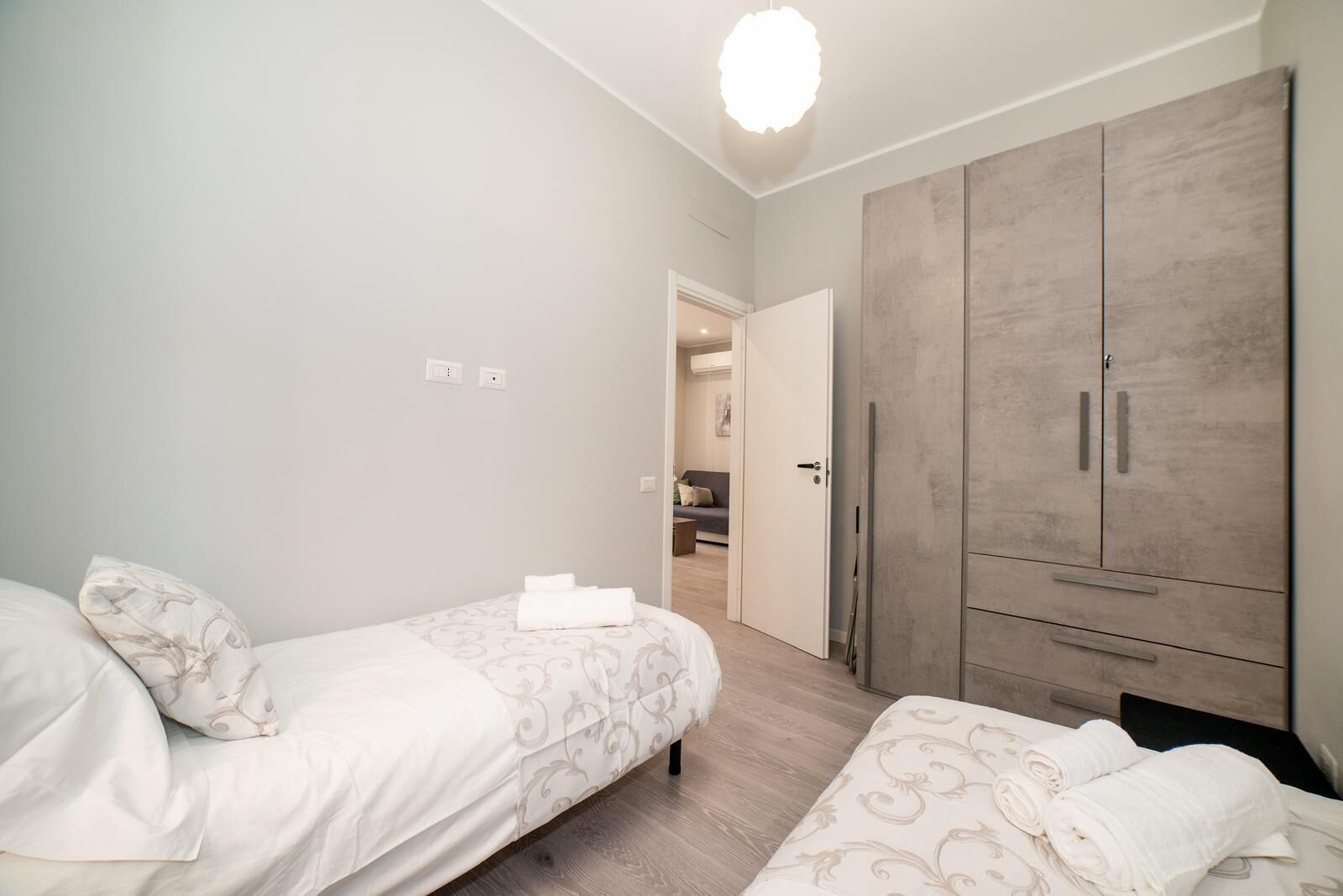 A bedroom with two beds, a wardrobe, and a door leading to a bathroom.