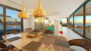 Zona pranzo moderna con tavolo in marmo, sedie nere e lampade a sospensione.