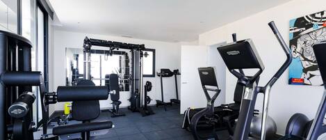A gym with exercise equipment, a wall-mounted TV, and a large window.