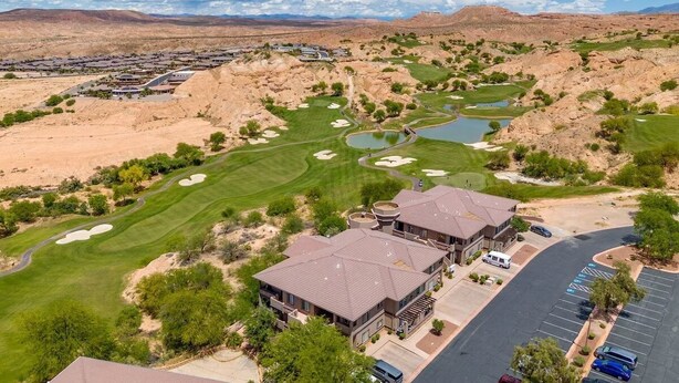 A golf course with a clubhouse, parking area, and surrounding desert landscape. - Spacious 2BR Condo with Secondary Suite on Wolf Creek Golf Course – Sleeps 8! (Mesquite)