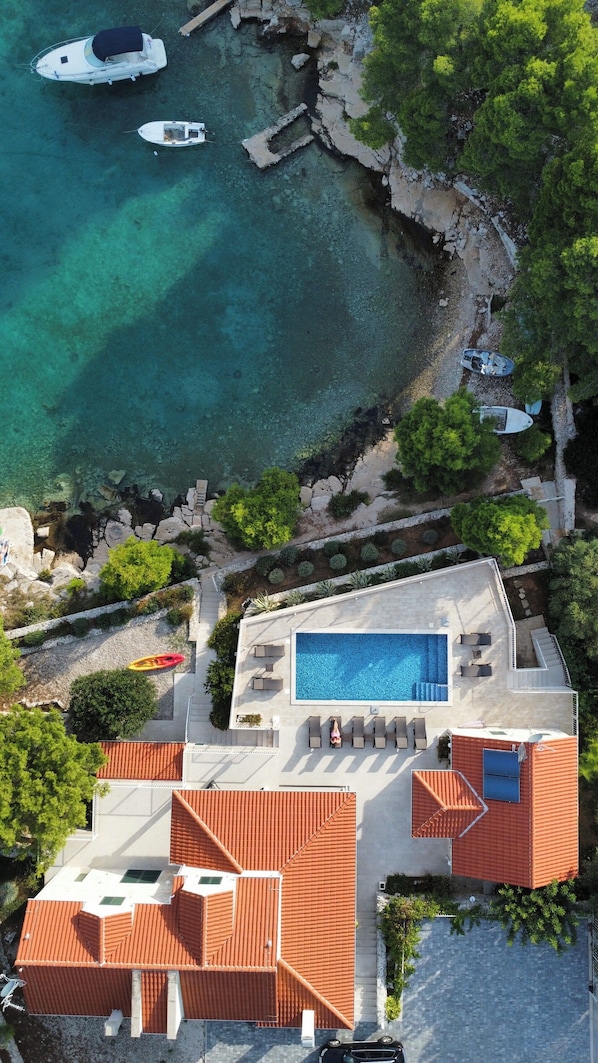 A residential property with a swimming pool, a boat dock, and a stone pathway leading to the water.