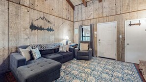 Una habitación acogedora con un amplio sofá modular, un sillón pequeño y una alfombra estampada.