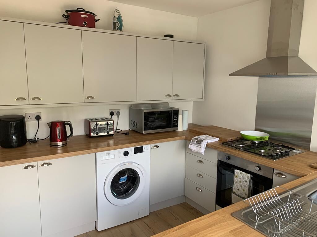Een kleine keuken met een wasmachine, een magnetron, een broodrooster en een kookplaat.