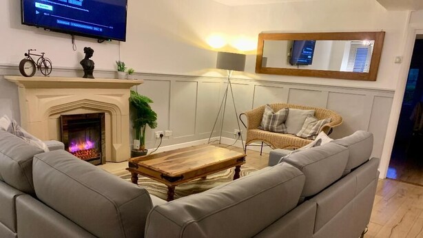 Una sala de estar con chimenea, un sofá, una mesa de centro y un televisor montado en la pared.