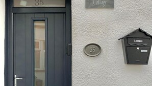 Una puerta azul oscuro con un panel de vidrio, un letrero de oficina postal y un buzón que dice 'Cartas' en una pared con textura.