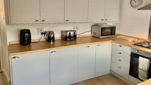 Una cocina moderna con armarios blancos, microondas, tostadora y hervidor.