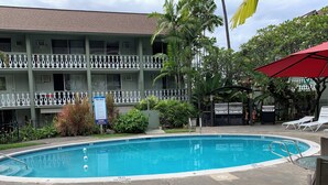 A swimming pool with lounge chairs, a grill, and a sign indicating pool rules.