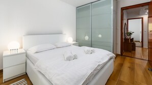 Un dormitorio moderno con una cama grande, un armario de vidrio y una mesita de noche con una lámpara.