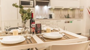 A dining table set with plates, glasses, and cutlery, a candle, and a bottle of wine in a modern kitchen. - Piasek Apt - Top Location, Patio, Tram&Bus nearby - by Rentujemy (Kraków)