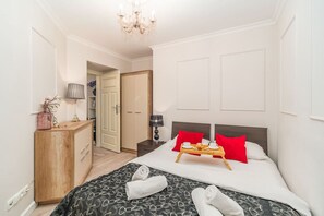 A hotel room with a bed, bedside table, lamp, and a wooden dresser. - Piasek Apt - Top Location, Patio, Tram&Bus nearby - by Rentujemy (Kraków)