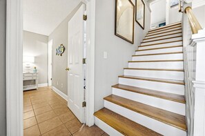 Eine Treppe mit Holzdielen und weißen Wänden, die zu einer Empore mit einer Tür führt.
