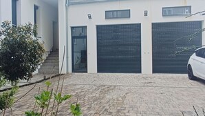 Ein modernes Gebäude mit überdachter Auffahrt, einem Fahrrad und einem weißen Auto vor der Tür.