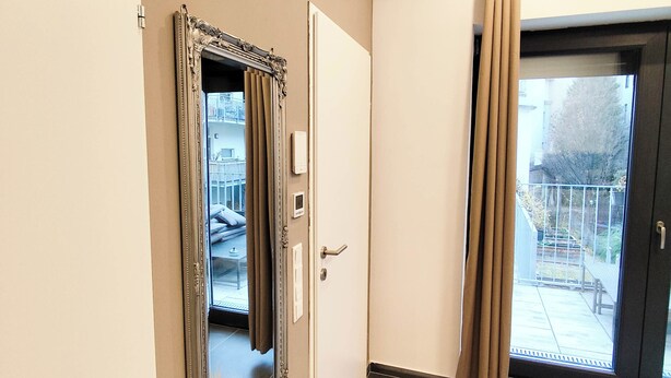 Eine Hotelhalle mit einem großen Spiegel, einer Tür, einer Uhr und Blick ins Freie.
