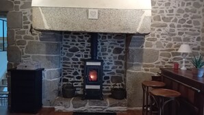 A stone fireplace with a modern wood-burning stove, a small table with a lamp, and a potted plant. - Charming country house with swimming pool in Vannes for family vacations (Vannes)