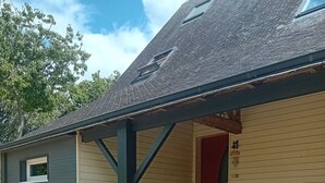 A small, single-story building with a covered porch and a stone staircase leading to a red door. - Charming country house with swimming pool in Vannes for family vacations (Vannes)