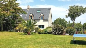 A house with a sloped roof, a front lawn, and a tennis court. - Charming country house with swimming pool in Vannes for family vacations (Vannes)