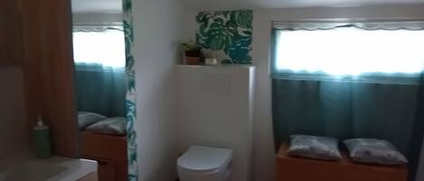 Une petite salle de bain comprenant des toilettes, un lavabo et un espace douche.