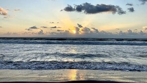 Een strand met golven en een zonsondergang.