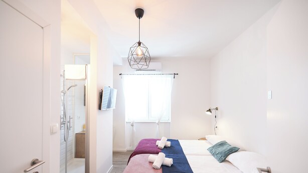 A modern hotel room with a bed, a shower, and a window with curtains. - Zaratino rooms (Zadar)
