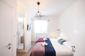 Una habitación de hotel moderna con cama, ducha y ventana con cortinas.