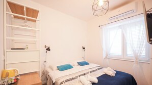 A bedroom with a bed, bedside tables, a wardrobe, and a window with curtains. - Zaratino rooms (Zadar)