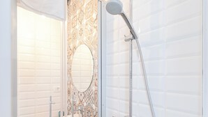 A modern bathroom with a glass-enclosed shower, a wooden vanity, and a patterned tile backsplash. - Zaratino rooms (Zadar)