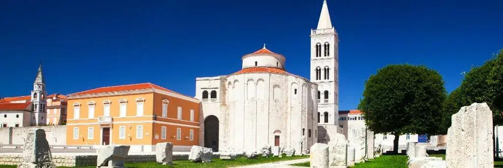 Un edificio histórico con una torre destacada y una cúpula, rodeado de otras construcciones y vegetación.