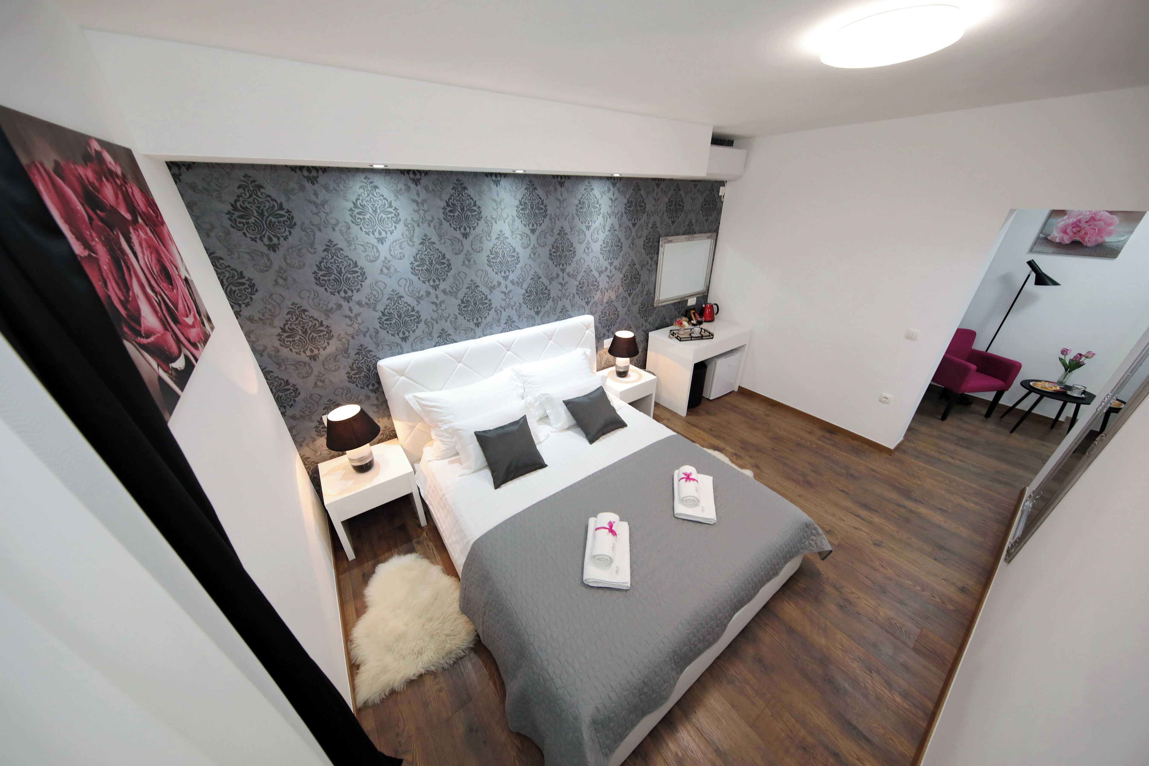 Een moderne hotelkamer met een groot bed, een bureau, een stoel en een spiegel.