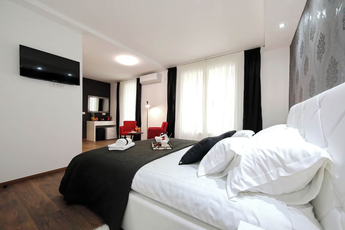 Ein Hotelzimmer mit Bett, Schreibtisch, Stuhl, Fernseher und einem Fenster mit Vorhängen.