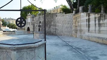 A courtyard with a stone wall, a fountain, and a metal structure with wheels.