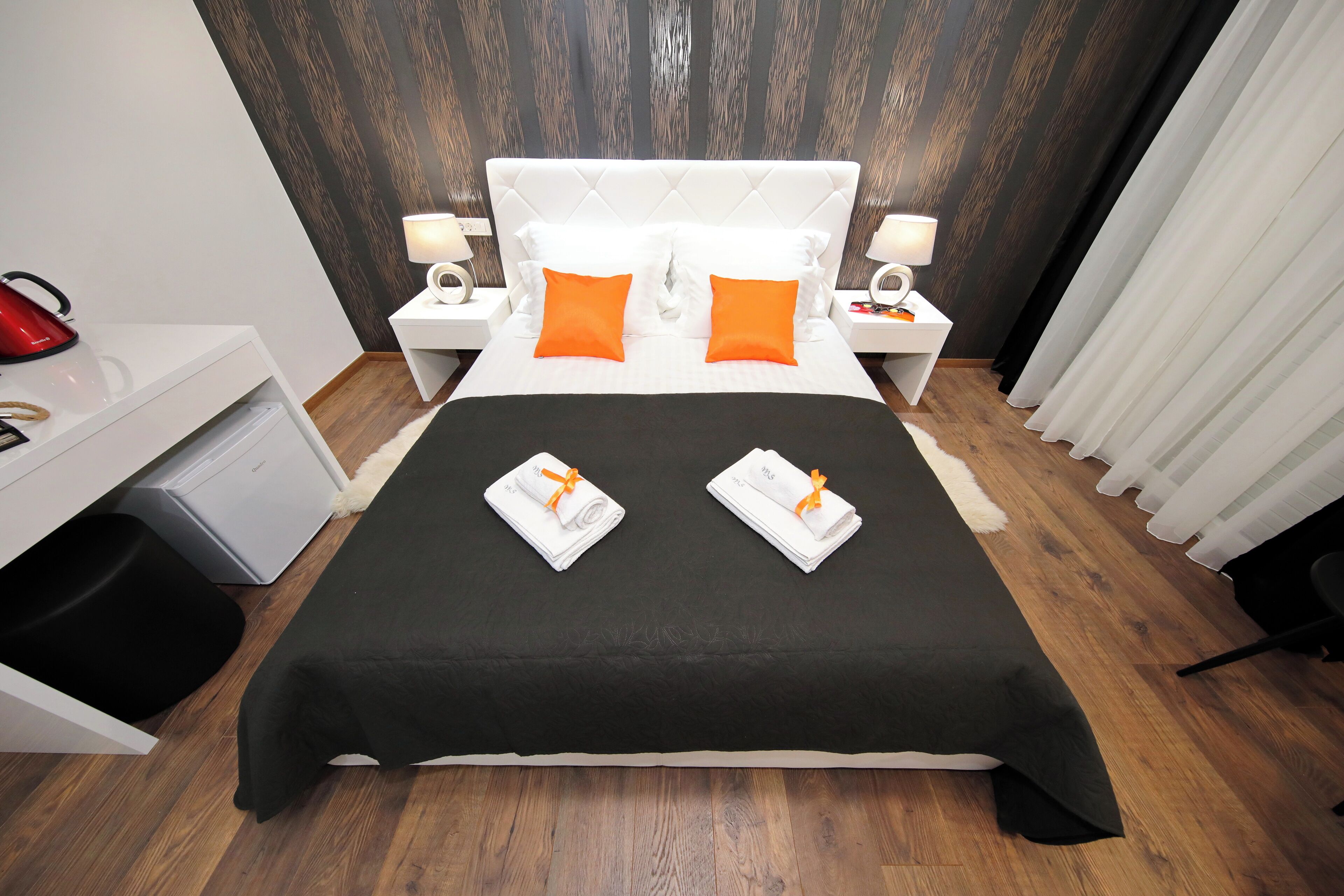A hotel room with a large bed, two nightstands, a desk, and a chair.
