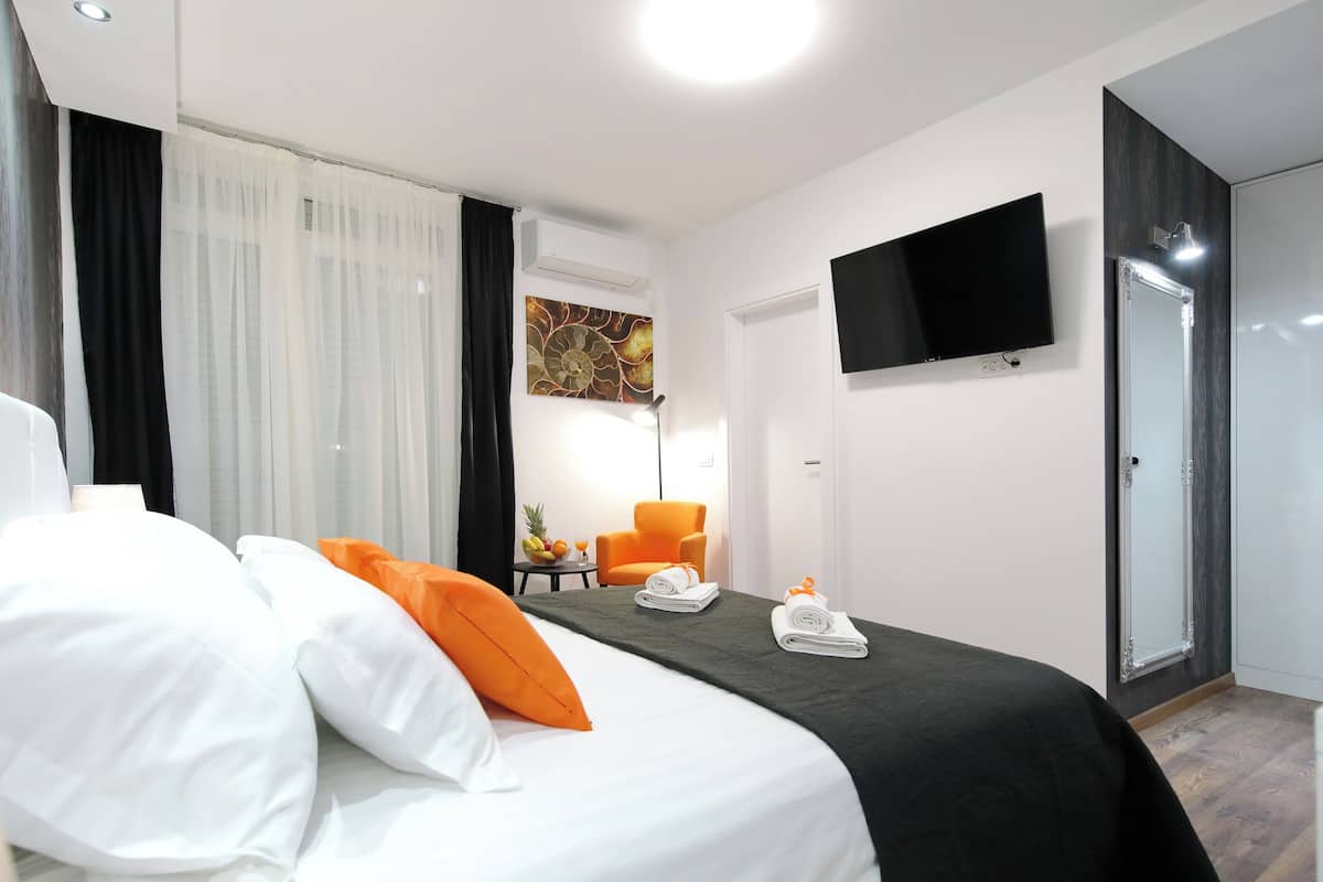 Ein Hotelzimmer mit einem Bett, einem Sessel, einem Fernseher und einer Tür.