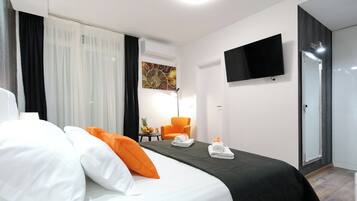 A hotel room with a bed, a chair, a TV, and a door.