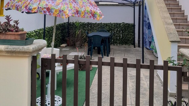 A courtyard with a colorful umbrella, a staircase, and potted plants.