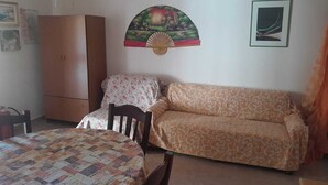 A room with a bed, a sofa, a wooden cabinet, and a wall-mounted decorative piece.
