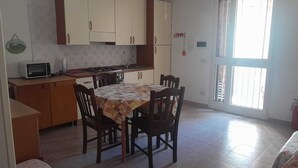 A compact kitchen with a dining table, chairs, a microwave, and cabinets.