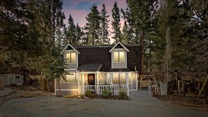 A two-story house with a dark roof, white trim, and a front porch with a railing. - Guest FAV Luxury Sun Chalet + Hot Tub + BBQ (Big Bear Lake)