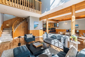 A spacious living area with a staircase, wooden beams, and a dining area.