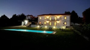 Ein zweistöckiges Gebäude mit Pool und Liegestühlen im Vordergrund.